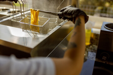 A chef thoughtfully frying food in a professional kitchen, showcasing culinary skills and equipment.