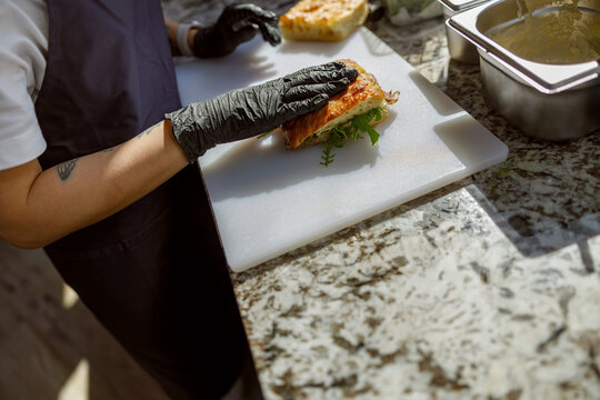 A skilled chef assembles a delicious sandwich, focusing on fresh ingredients and strict hygiene standards