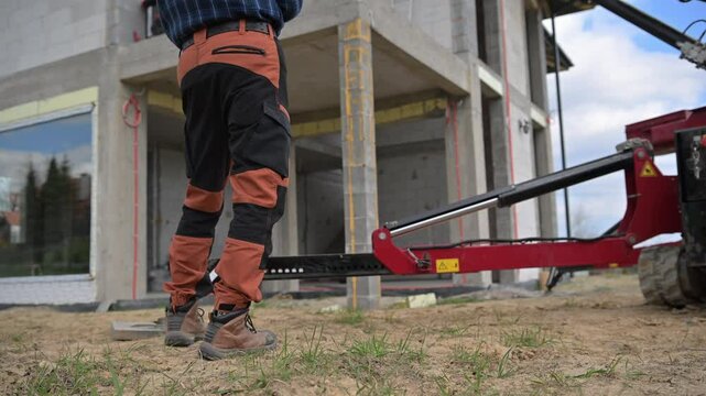 Construction Worker Operates Machinery at Building Site in Peaceful Suburban Area During Daylight Hours