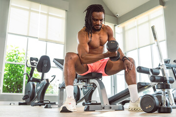Obraz premium A man is lifting weights in a gym. There are several pieces of gym equipment in the background, including a stationary bike, a bench, and a weight rack