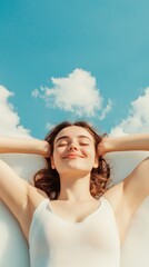 Young woman in a white tank top lying on a white surface with hands behind her head, eyes closed, enjoying a peaceful moment against a blue sky and white clouds