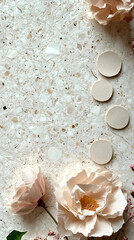 Four pale pink, slightly irregular, round ceramic coasters arranged diagonally on a light grey speckled surface with two pale pink flowers with green leaves to the left and right