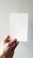 Close-up of a hand gently holding a blank postcard Vertical orientation, white background , card, elegant