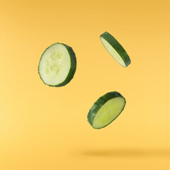 Fresh raw cucumber  falling in the air isolated on yellow background. Food levitation or zero...