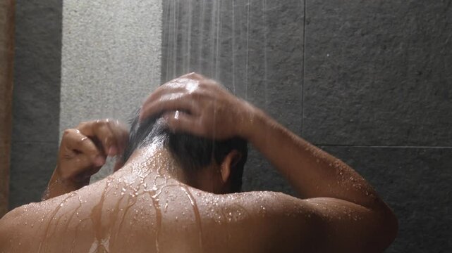 A man is taking a shower and washing his hair.