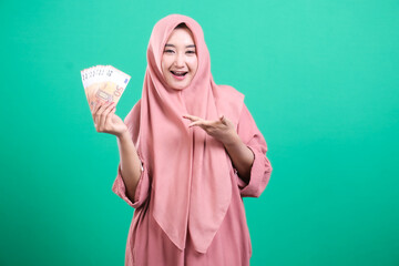 Financial prosperity showcased by cheerful lady in hijab, holdin