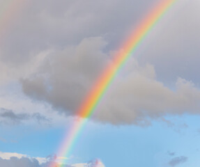 amazing bright rainbow in beautiful evening blue cloudy sky after rain and thunder with flash sun light streaming thruogh the clouds, weather thunderstorm concept