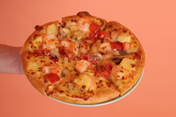 Hand holding Hawaiian pizza