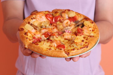 Hand holding Hawaiian pizza