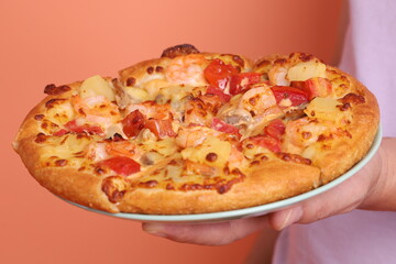 Hand holding Hawaiian pizza