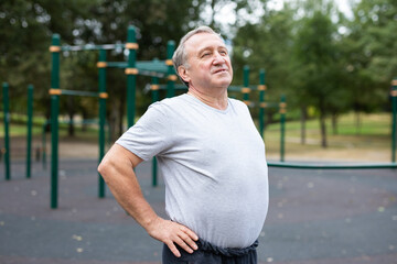 Elderly man doing gymnastics on an outdoor sports ground