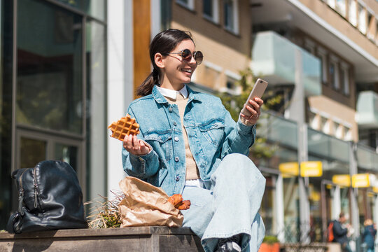 With a big smile and a Belgian waffle, a woman explores the city, combining indulgent treats, cultural discovery, and modern travel content