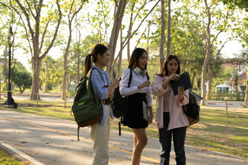 Obraz premium Three women are walking in a park, one of them is carrying a backpack. Scene is relaxed and casual, as the women are enjoying a leisurely walk in the park 