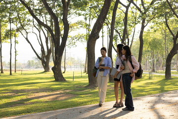 Fototapeta premium Three women are walking in a park, one of them is carrying a backpack. Scene is relaxed and casual, as the women are enjoying a leisurely walk in the park 