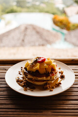 Pancake with mango, fruit, granola and syrup  for breakfast. Delicious tropical breakfast on the island at the hotel	