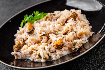 Rice seafood risotto mussel, shrimp, prawn, rapan, squid dish fresh gourmet food background on the table rustic food top view copy space