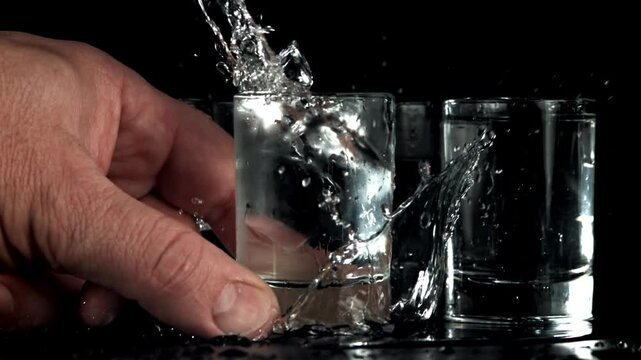 The man puts a glass of vodka on the table. Filmed on a high-speed camera at 1000 fps. High quality FullHD footage