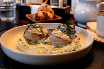 Fish cutlets, meatballs, salmon hamburger steak garnished with fresh dill, served with creamy mushroom sauce and sides in a restaurant setting close up. Fine eating