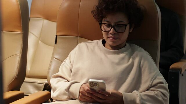 Happy Woman traveling by plane and Write notes while traveling  in airplane. African American business female sitting in airplane during flight in first class seat