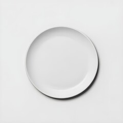 A simple white ceramic plate centered on a white surface casting a soft shadow on the background