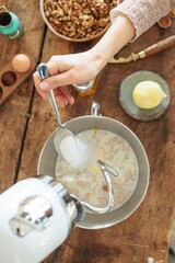 In a warm, inviting kitchen, hands expertly blend ingredients for Balkan Cozonac using a stand mixer. This sweet bread combines flavors of walnuts, vanilla, and cocoa for festive celebrations