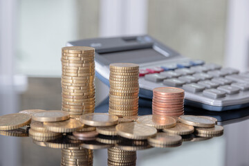 Stacked coins and calculator with a blurred background.