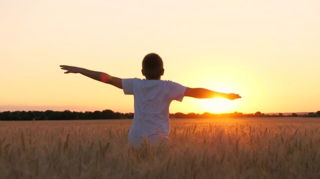 Happy male teen running on wheat field with open hands enjoy freedom at sunset sunrise back view closeup. Boy kid teenager relaxing imagine flying at dusk rye meadow sun sky forest horizon
