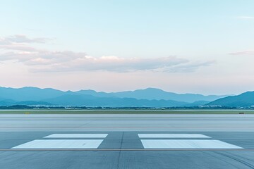 Empty airport tarmac at dawn, mountains in the distance