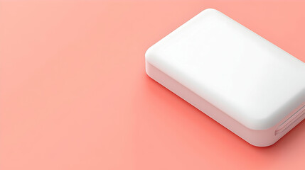 A white rectangular box, simple and modern design, sits on a coral-pink surface.  It's a portable device, potentially a power bank or similar electronic accessory