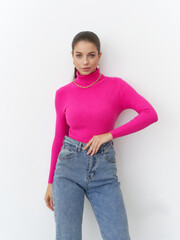 Fototapeta premium Striking pose of a confident woman in vibrant pink sweater at a modern studio setting