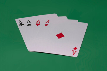 Close-up of four ace cards on a green background.