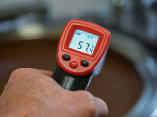 A person is holding a food checking digital thermometer that reads 57 degrees