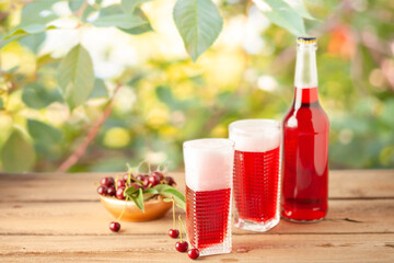 Boozy Refresing Cold Hard Cherry Cider in a Pint Glass and Bottle on wooden table. Copy space