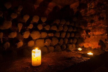 Burning candle illuminating dark cellar with firewood in the background