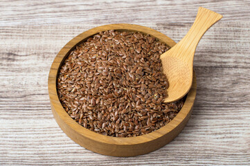 Flax seed in a wooden bowl on a dark background. Horizontal, top view. Healthy eating, diet, omega3.