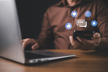 A person in a brown shirt uses a smartphone and laptop simultaneously with floating social media...