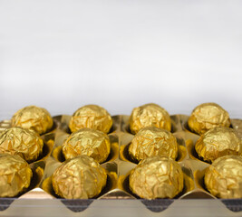 Close-up of a box of golden chocolates on white background with copy space
