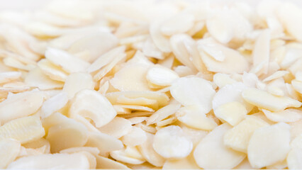 Close up of almond flakes on white background, healthy food concept. Selective focus.