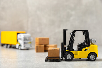 Yellow forklift and yellow truck on bright background. Logistics concept. Logistics and supply chain management of online shopping. Delivery of goods or products to the store worldwide. Cardboard box.