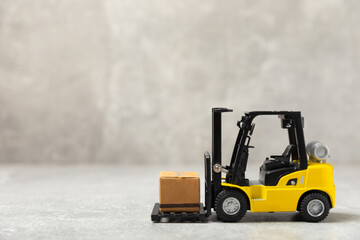 Yellow forklift and yellow truck on bright background. Logistics concept. Logistics and supply chain management of online shopping. Delivery of goods or products to the store worldwide. Cardboard box.