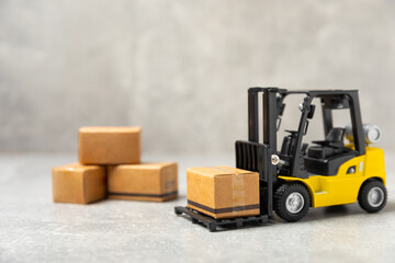 Yellow forklift and yellow truck on bright background. Logistics concept. Logistics and supply chain management of online shopping. Delivery of goods or products to the store worldwide. Cardboard box.