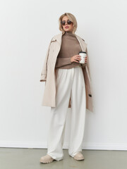 Elegant woman poses in contemporary fashion with coffee in stylish studio setting