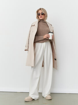 Elegant woman poses in contemporary fashion with coffee in stylish studio setting