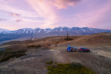 Scenic mountain camping with trailer camper under pink sky at sunset