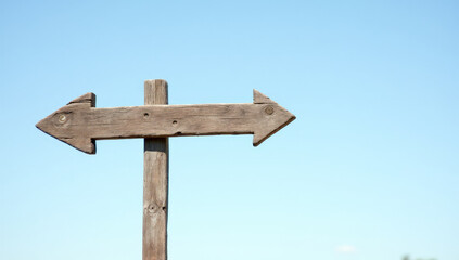 An empty wooden signpost against a blue sky background