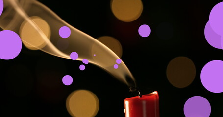 Image of violet and yellow dots over fading out candle on black background