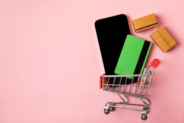 Online shopping concept.Cardboard box and shopping bags in a trolley on a bright colored...