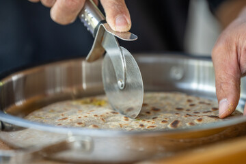 A person is cutting a tortilla with a pizza cutter
