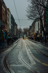 Dublin, Ireland - February 15 2025: Dublin City Centre - A yellow tram in between buildings on an overcast afternoon