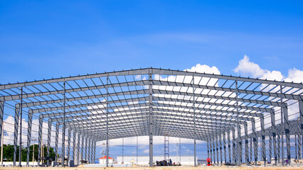Metal structure of large industry warehouse factory building with workers are working in construction site against blue sky background, front view with copy space